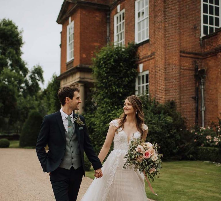 Bride in Madi Lane dress walks hand in hand with new husband at Iscoyd Park