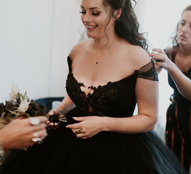 Bride has her black bridal gown done up on the morning of her wedding