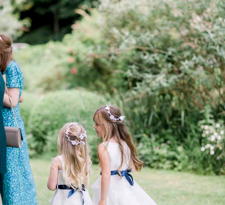 Flowers girls wear white dresses complete with royal blue waistbands 