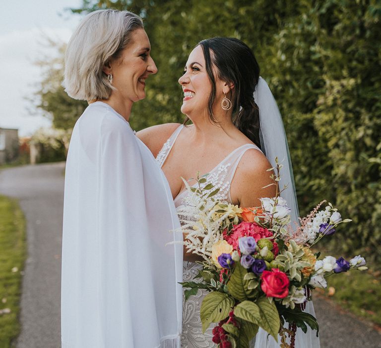 LGBTQI+ wedding a country house wedding venue in Devon as brides pose together with colourful wedding bouquet