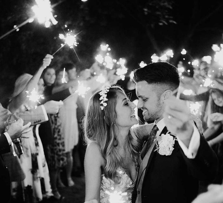 Evening sparkler send-off for bride in white flower headband and groom 