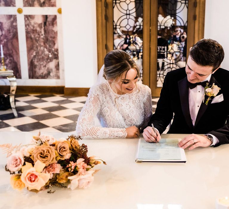 Bride and groom sign their wedding registry together