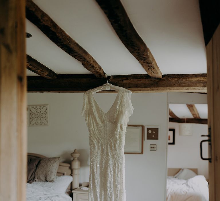 Bride's beaded wedding dress hangs from the ceiling