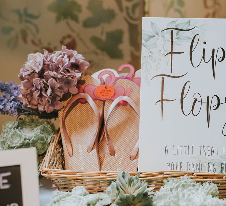 Wicker basket full of flip flops for wedding guests to use if their feet were hurting and wanted to dance with leaf design sign