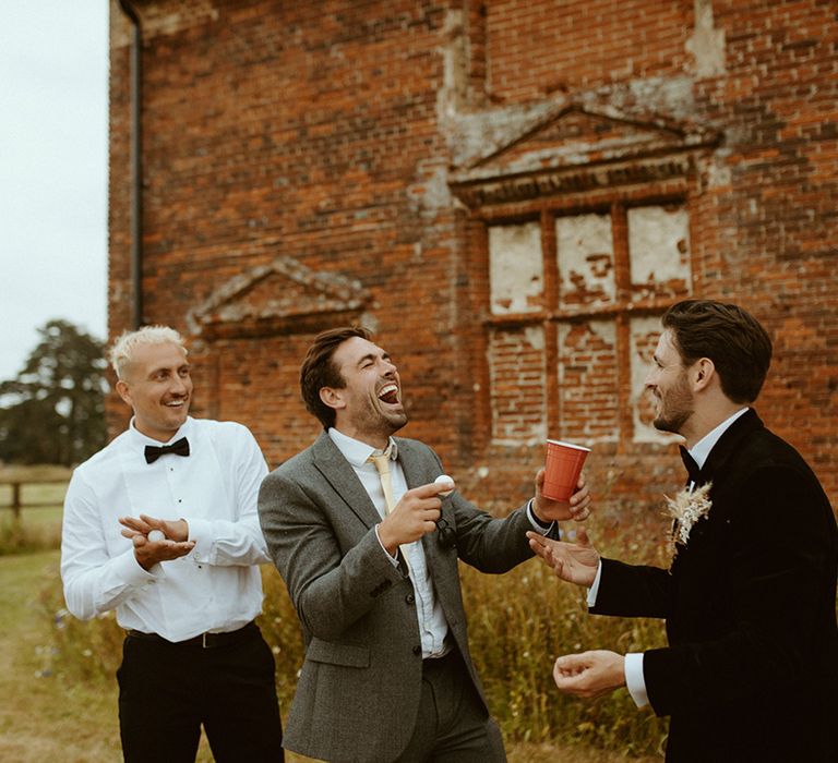 Groom plays beer pong with the groomsmen and other wedding guests