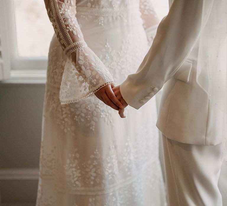 Brides hold hands on their wedding day during ceremony