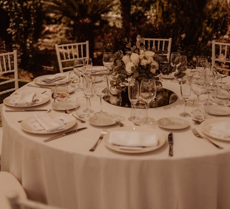 Simple tablescape complete with white tablecloths and floral bouquet centrepieces 