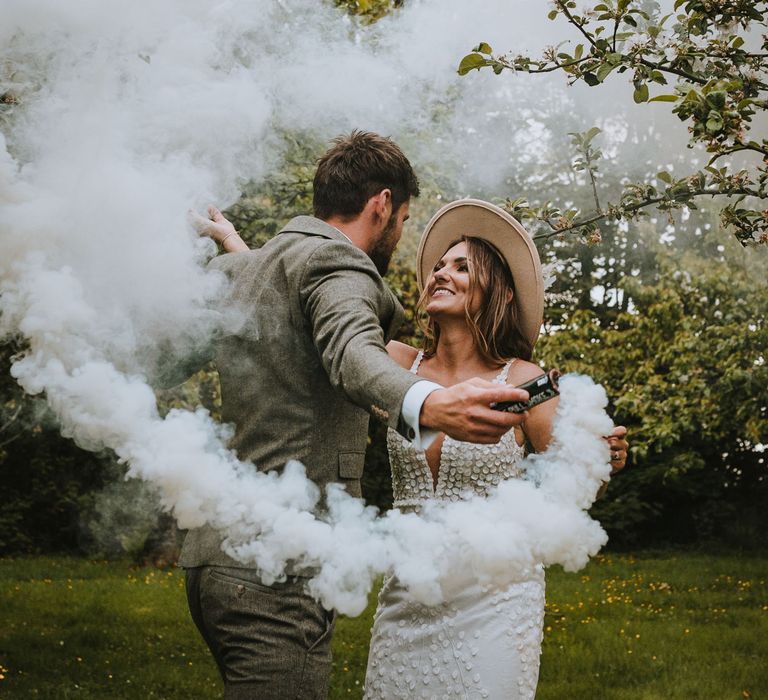 Bride and groom embracing on the grounds of The Green Cornwall doing a grey smoke bomb photo shoot 