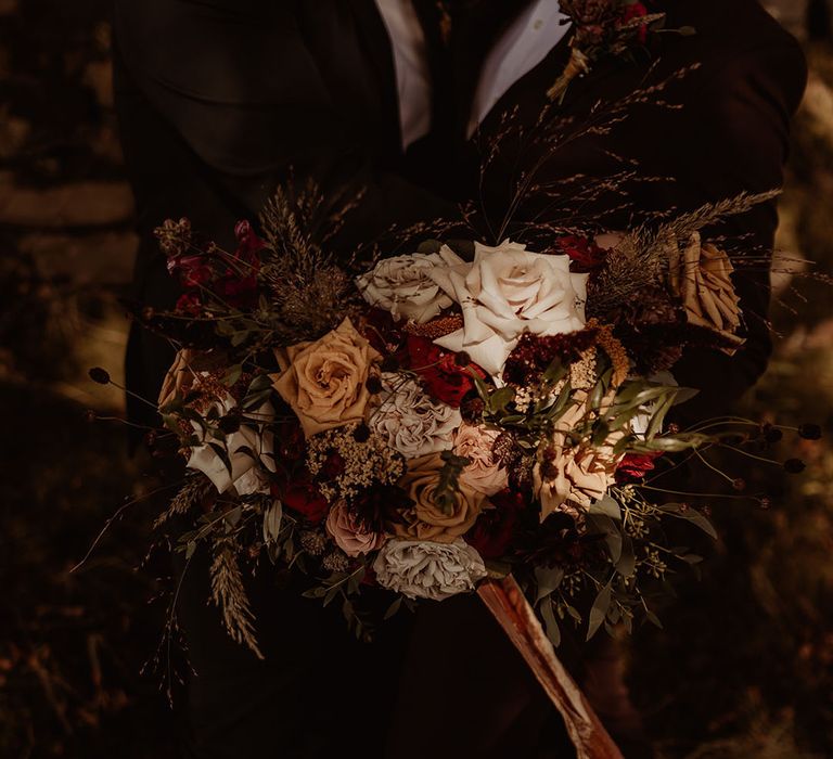 Gorgeous warm autumnal wedding bouquet tied with a velvet ribbon 