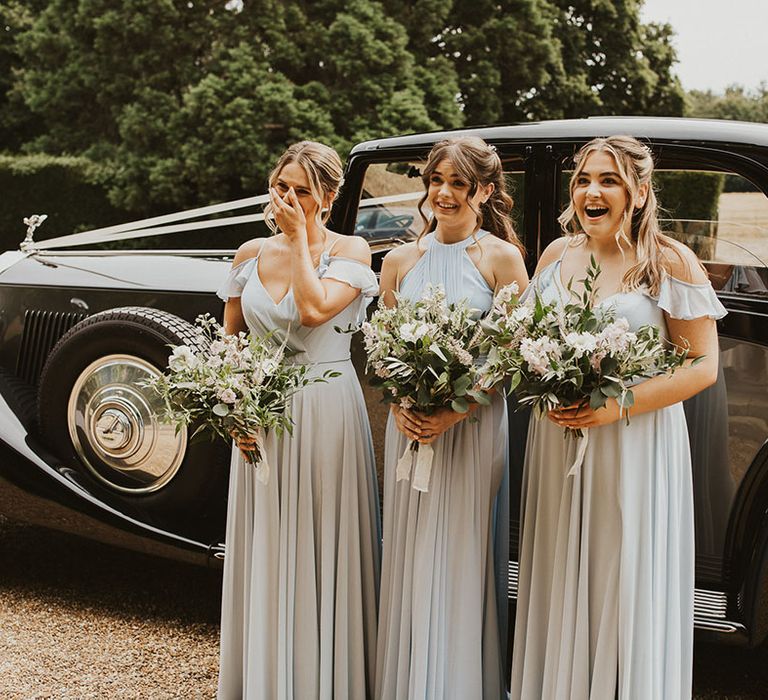 Bridesmaids in pastel blue dresses get their first look at the bride 