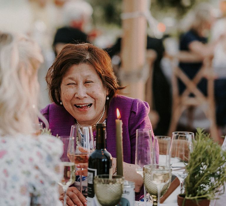 Mother of the bride in a purple blazer laughing at the wedding reception 