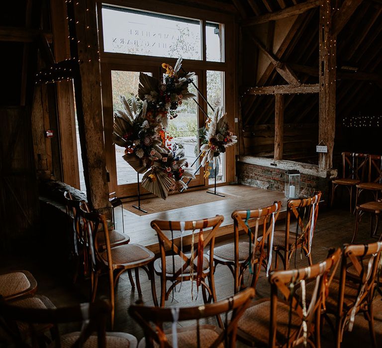 Wooden chairs have colourful ribbons decorating the chair backs with diamond altar decoration with dried flowers 