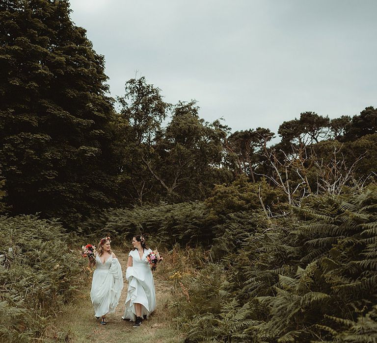 Bride in Freda Bennet wedding dress lifts her skirt as she walks with bride 