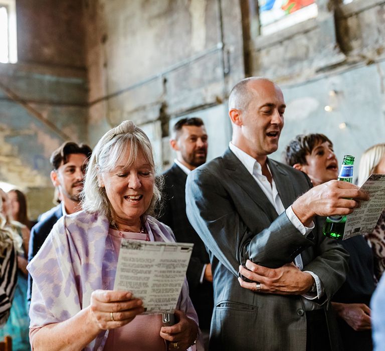 Wedding guests sing at The Asylum Chapel during ceremony 