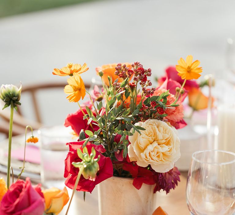 Colourful flowers line wooden banquet tables for outdoors reception in Mexico 