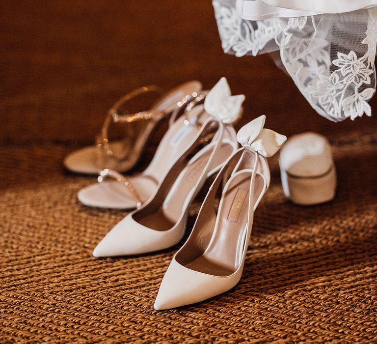 The bride's white pointed wedding shoes with bow detail and gold sparkly stroppy reception shoes 