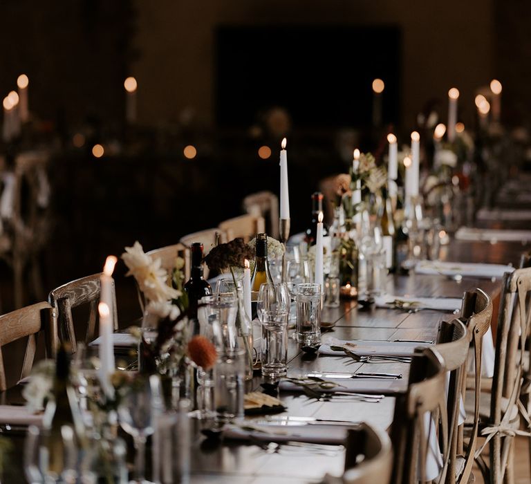 White taper candle with neutral wedding flowers decorating the dimly lit and cosy Bake Barn wedding venue 