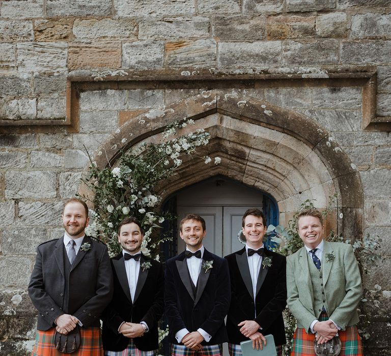 Groom and groomsmen in tartan trousers or kilts for the wedding 