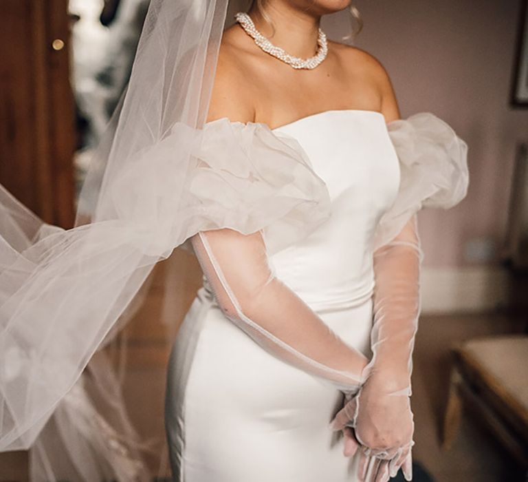 The bride wears a fitted wedding dress with puff sleeves and a rental veil 