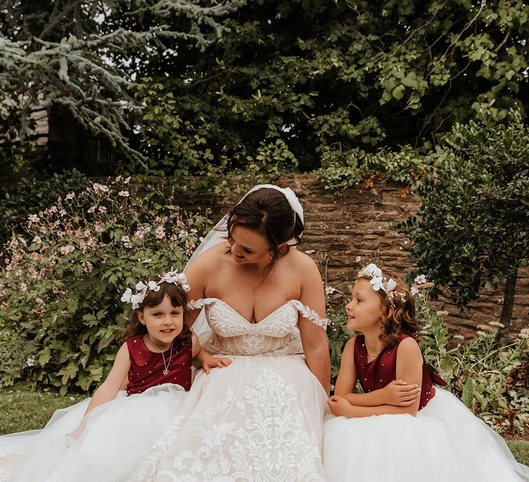 Flower girls in red and white dresses sitting with the bride in a Martina Liana wedding dress 