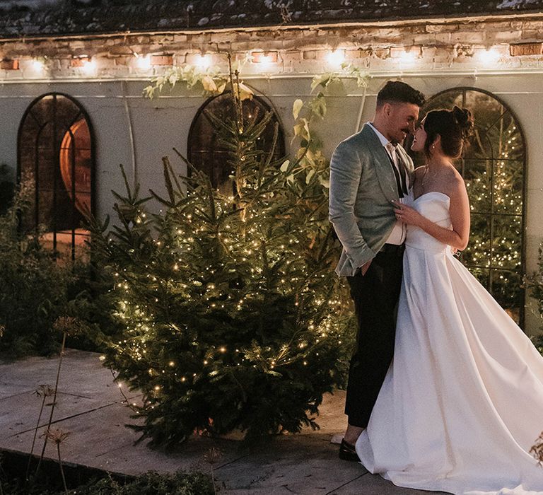 Christmas tree decoration with the bride and groom posing on their festive wedding day 