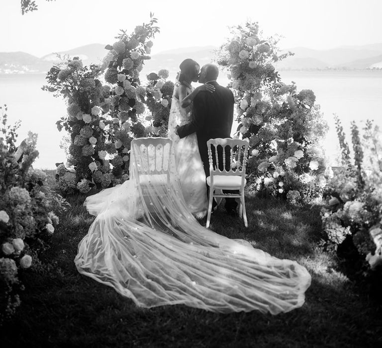 Bride and groom share their first kiss as a married couple at outdoor wedding ceremony 