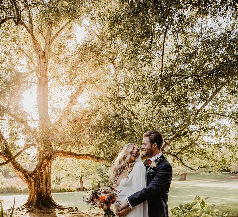 Bride wearing long sleeve wedding dress with the groom in a three piece navy suit with a light grey waistcoat 