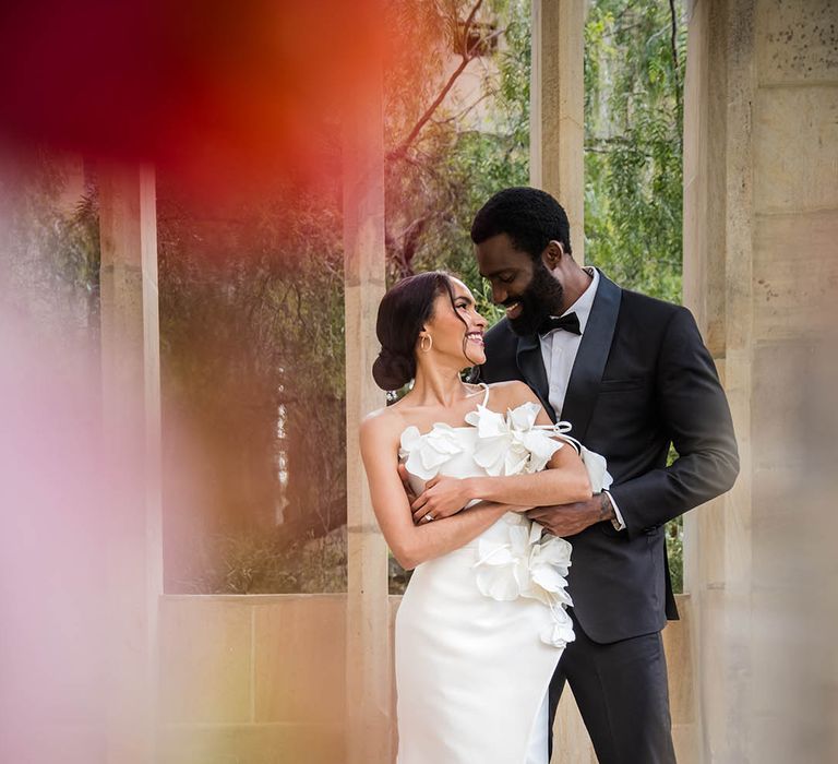 Bride in 3D flower wedding dress with groom in black tux 