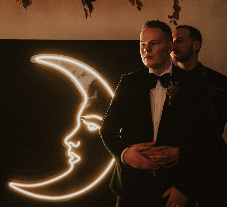 Moon neon wedding sign with two grooms embracing each other for couple portrait 