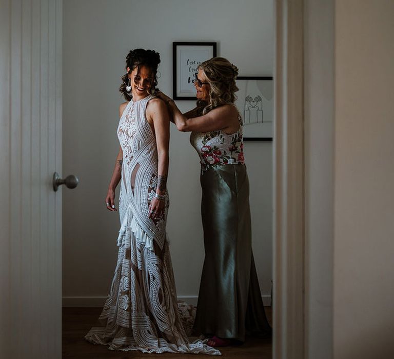 Bridesmaids helps the bride into her boho lace Rue de Seine wedding dress 