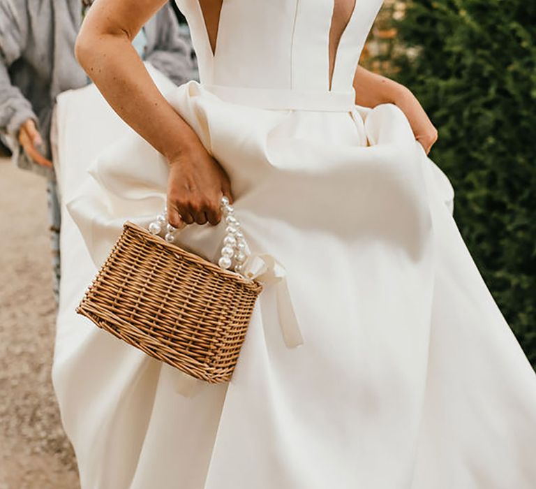 Bride holding a wicker bag with pearl handles on her wedding day by Jessica Hopwood Photography