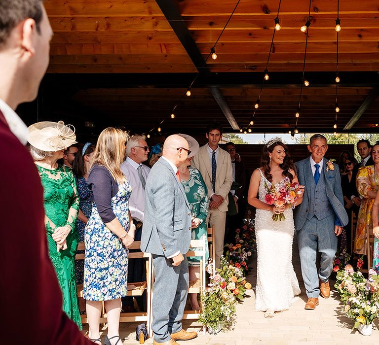 Father of the bride in a blue wedding suit walking the bride down the aisle 