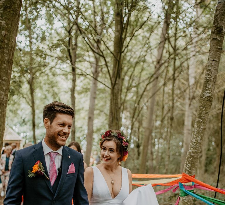 Bride and groom at forest wedding with rainbow wedding decor