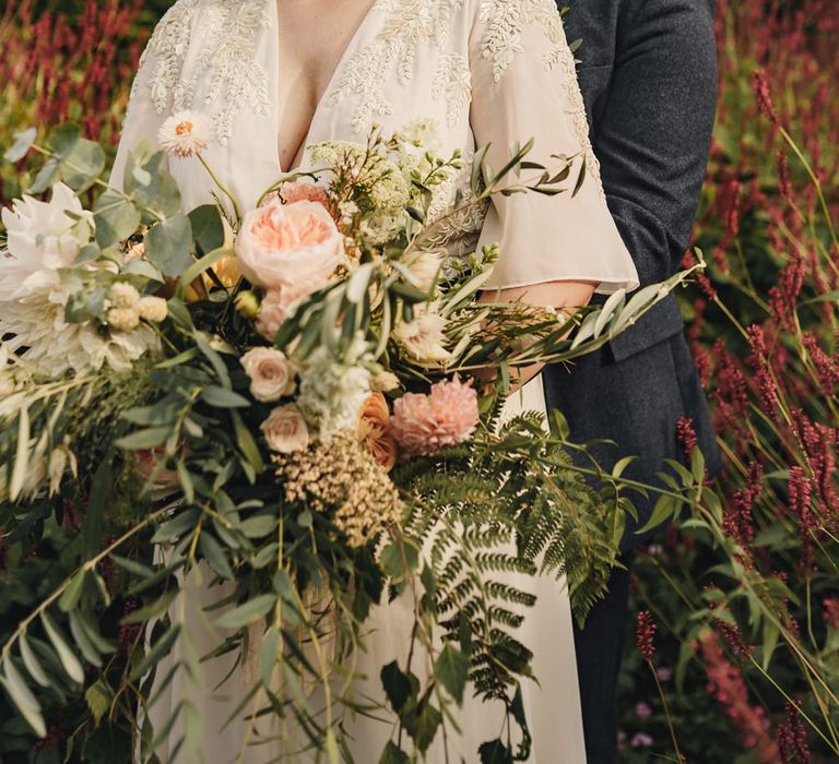 Groom embracing his bride in boho wedding dress