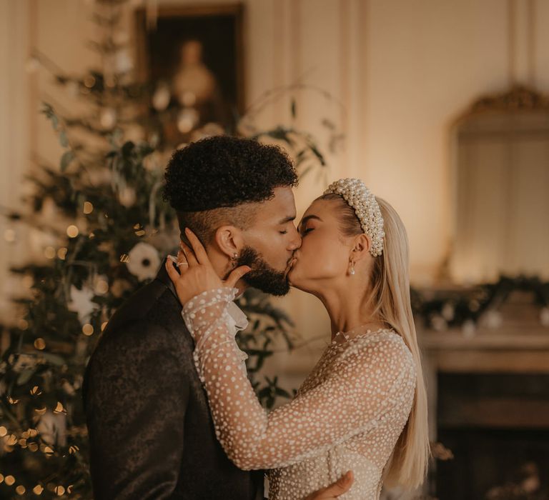 Bride in long sleeve sequin  wedding dress kissing her groom at Gosfield Hall