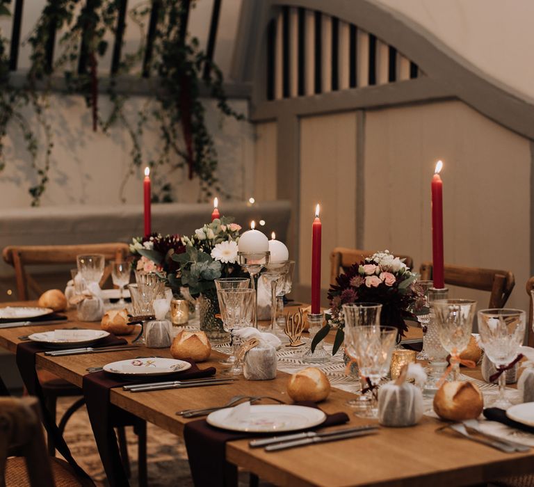 Rustic reception table decorated with table runner, candles and vintage tableware