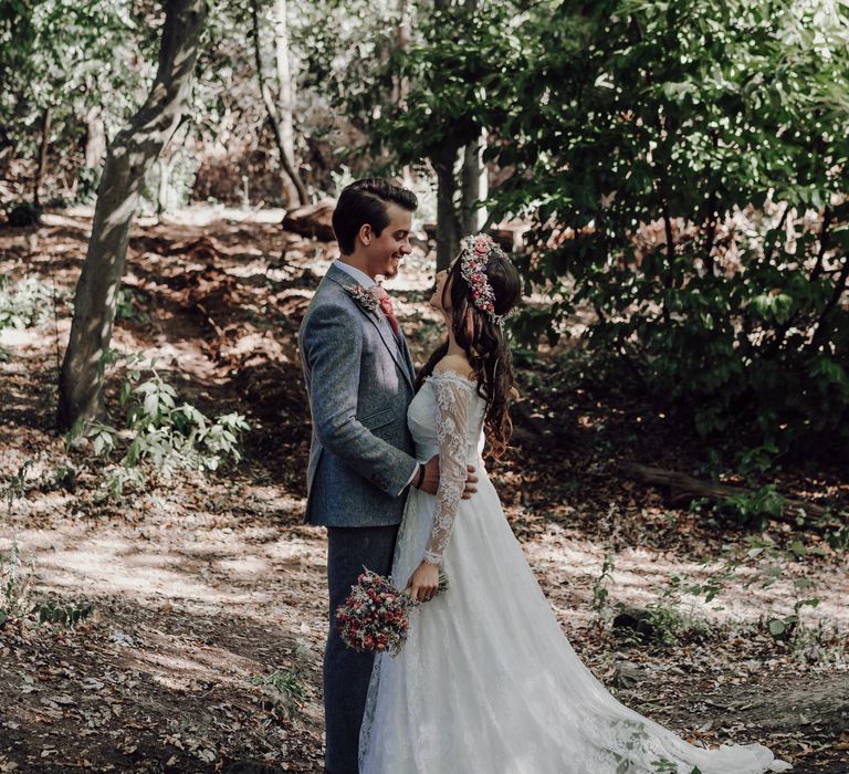 Bride and groom embrace in woodland shoot with dried flowers