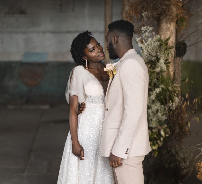 Groom in beige suit looking into his brides eyes 