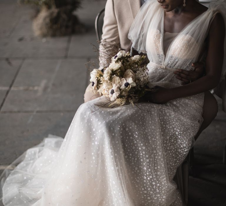 Bride in sequin wedding dress holding an anemone bouquet 