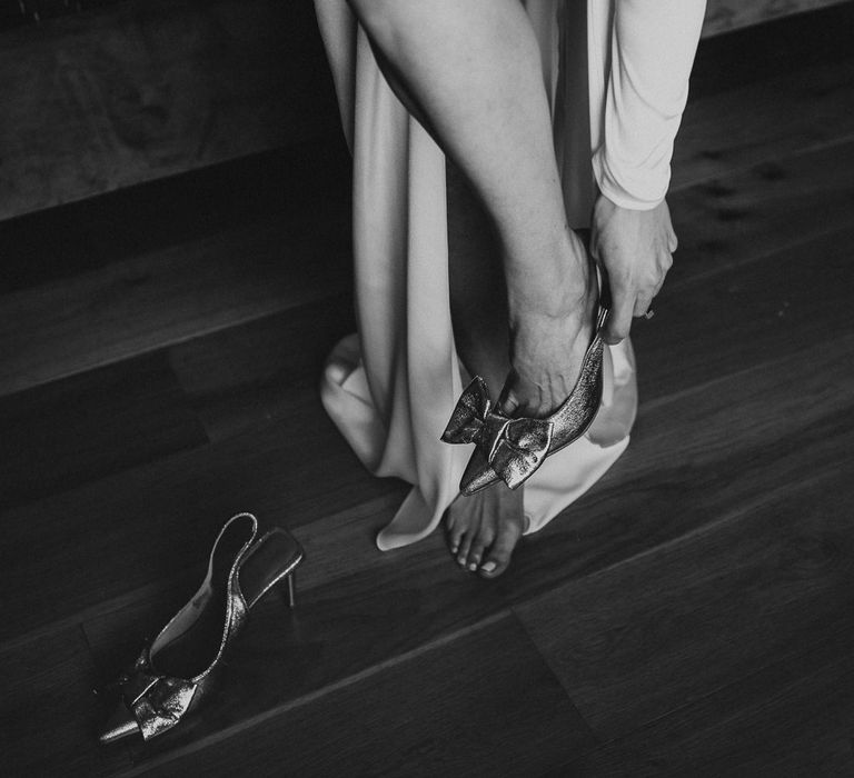 Bride puts on gold bow slingback heels on her wedding morning