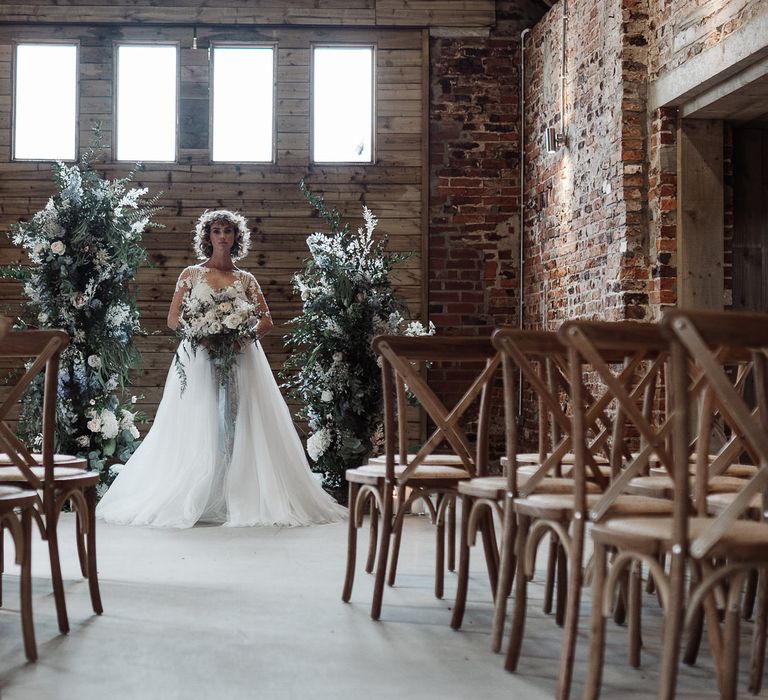 The bride standing alone at the altar with a romantic wedding bouquet