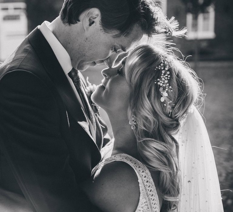 Bride in pearl headband hugs groom in the grounds at Iscoyd Park wedding