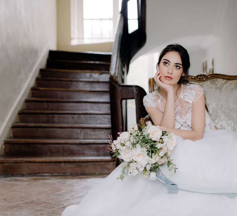 The bride sitting in the grand hallway of Chateau de la Ruche