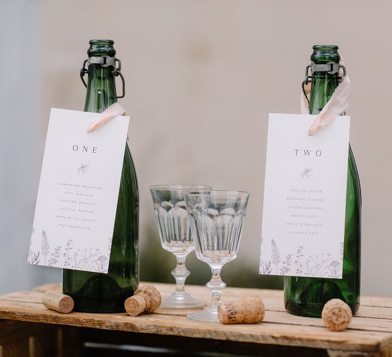 Wine bottle seating plan with white name card and pink ribbon