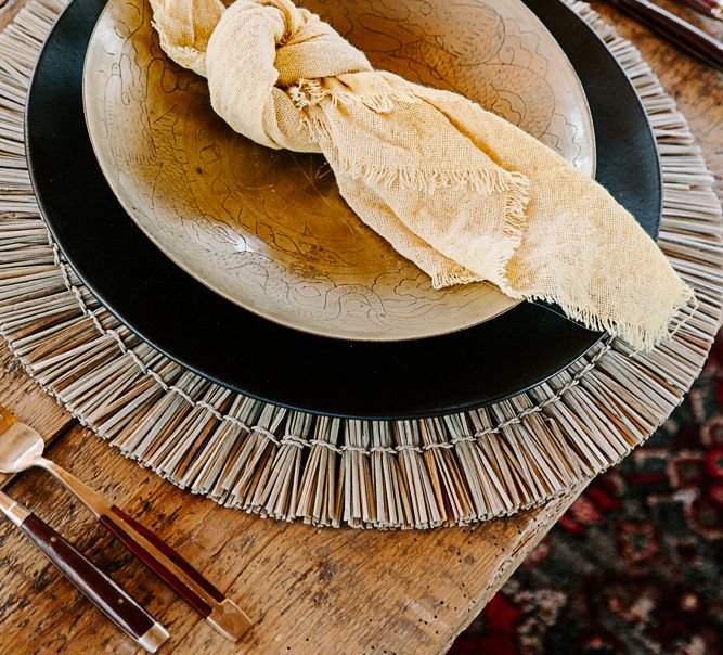 Fabric napkin tied in a knot upon plate on rattan placemat