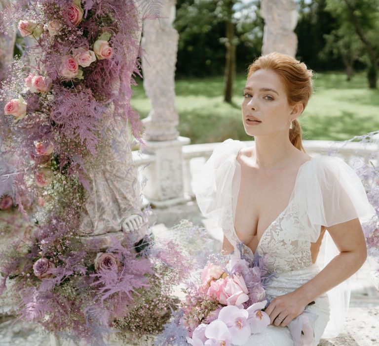 Bride wears low cut lace gown with chiffon sleeves 