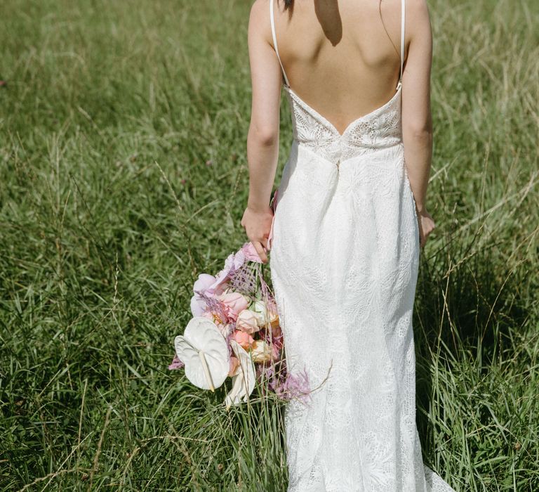 Dark haired bride walks away from the camera wearing a low back wedding gown