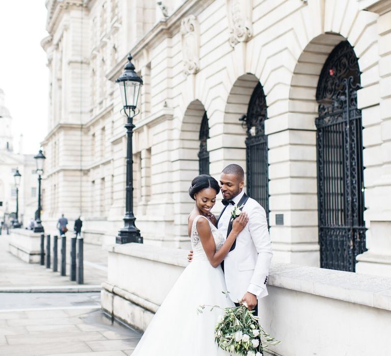 Bride & groom sit together outside white building in London