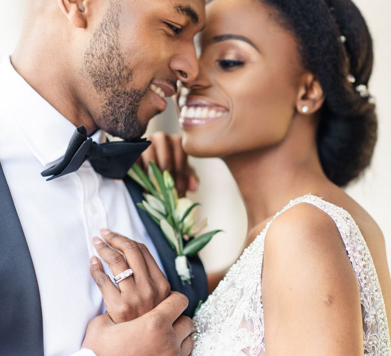 Groom holds brides hand whilst embracing outdoors