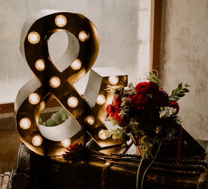 Vintage suitcase, marquee light ampersand and red rose wedding bouquet 